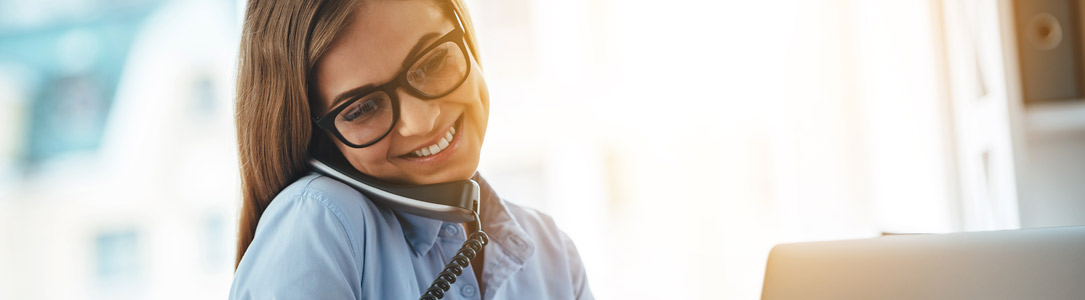 Woman with glasses on her landline phone from Alpine Communications